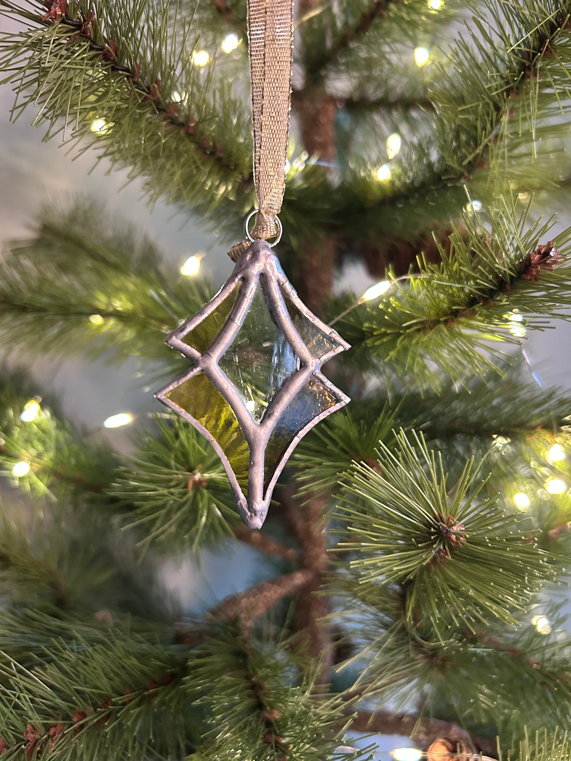 Decorative star-shaped ornament on a Christmas tree with lights.