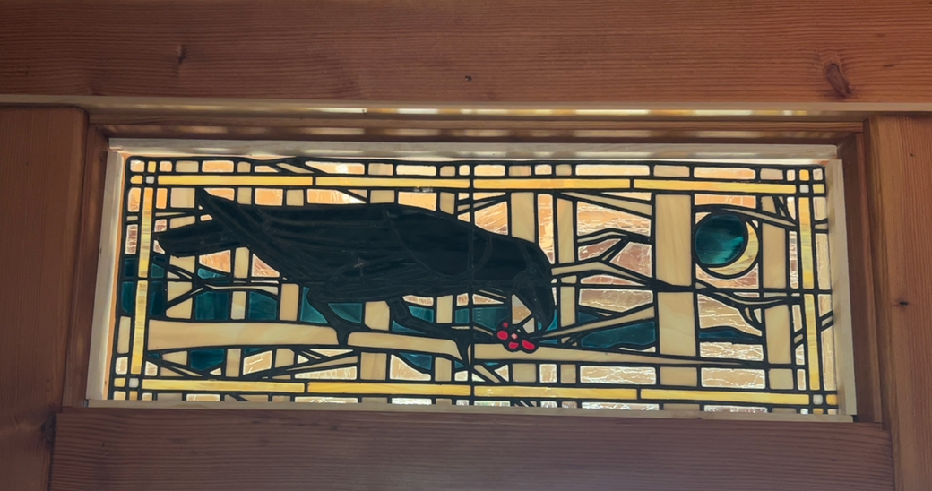 Stained glass panel with a bird design on a wooden frame